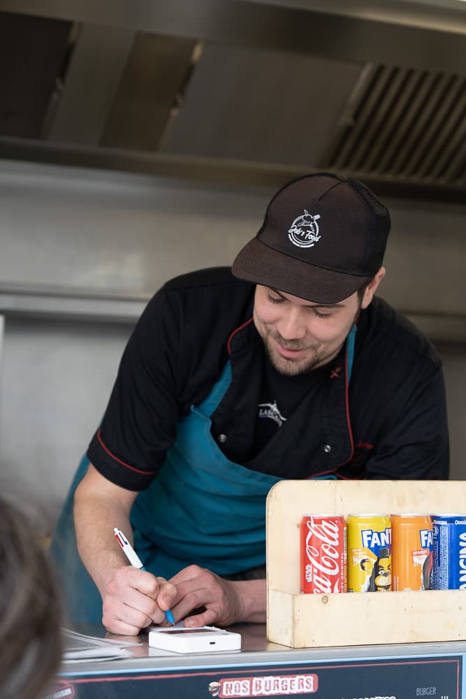 Yann prend une commande au comptoir du food truck, en plein service